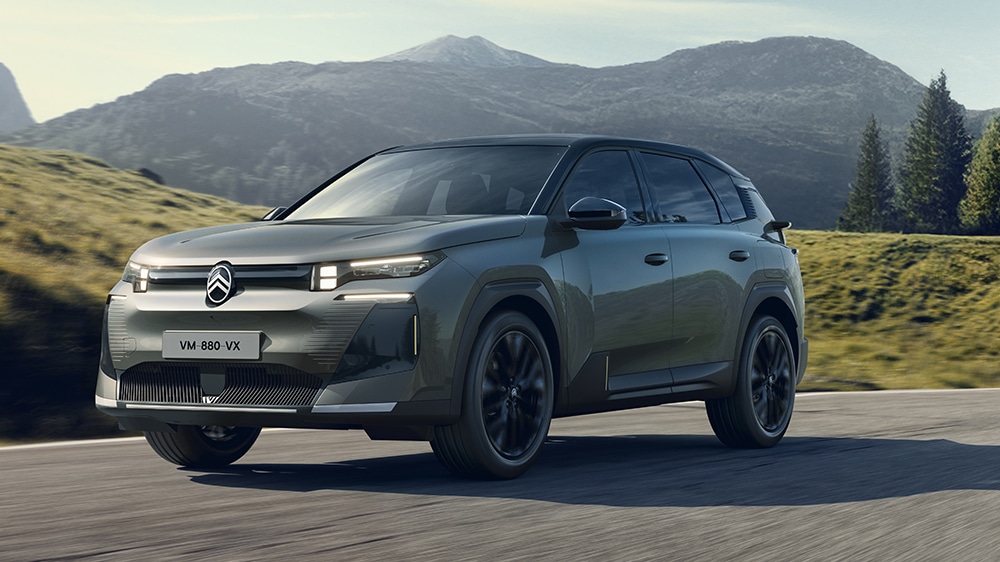 Auf diesem Bild ist ein grauer Citroën- C5 Aircross SUV zu sehen, der auf einer Straße durch eine malerische Berglandschaft fährt.
