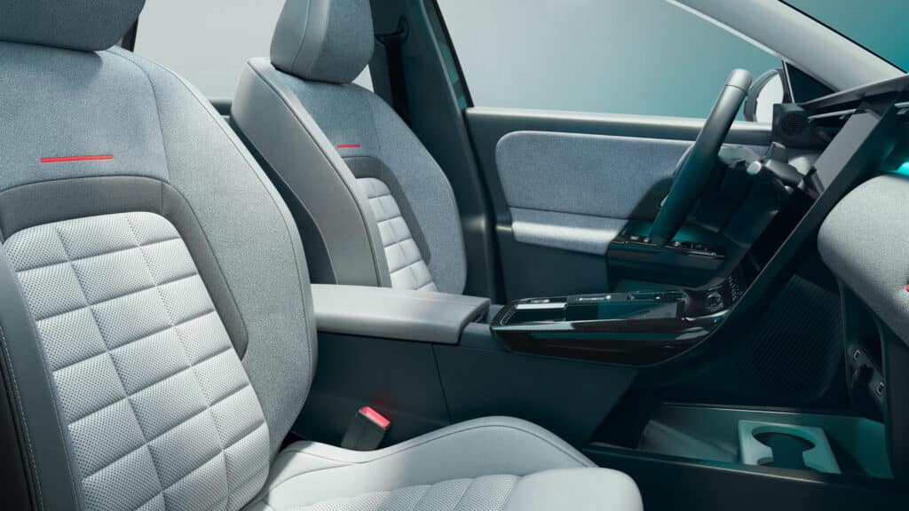 Die Aufnahme zeigt den hellen und modernen Innenraum eines Fahrzeugs mit einem Schwerpunkt auf die Vordersitze und den Fahrerbereich.