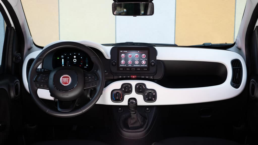 Auf diesem Bild ist das Cockpit eines Fiat Pandina mit Lenkrad, Armaturenbrett, Infotainment-System und Schaltknauf zu sehen.